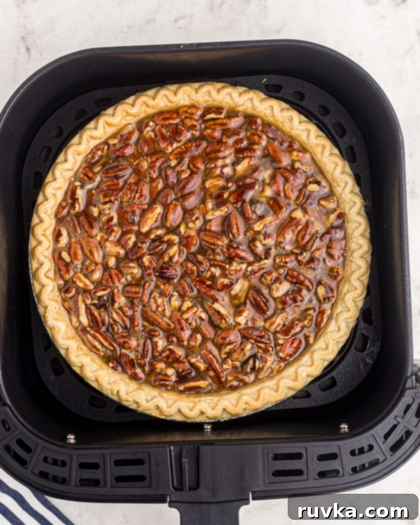 Perfect Air Fryer Pecan Pie 6 An unbaked pecan pie, perfectly assembled and placed in an air fryer basket, ready for cooking.