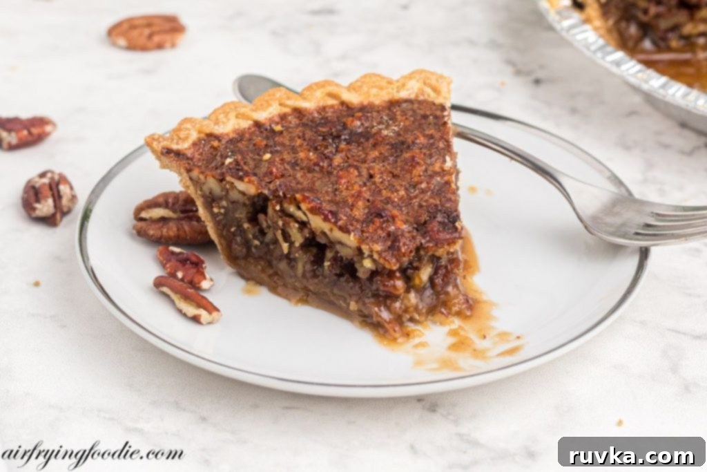 Perfect Air Fryer Pecan Pie 9 A delectable slice of pecan pie on a white plate, with a bite taken out, revealing its rich, gooey filling and crisp crust.