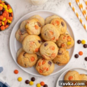Easy Air Fryer Sugar Cookies 7 Baked sugar cookies scattered on a white plate, with Reece's Pieces candy scattered around the plate.
