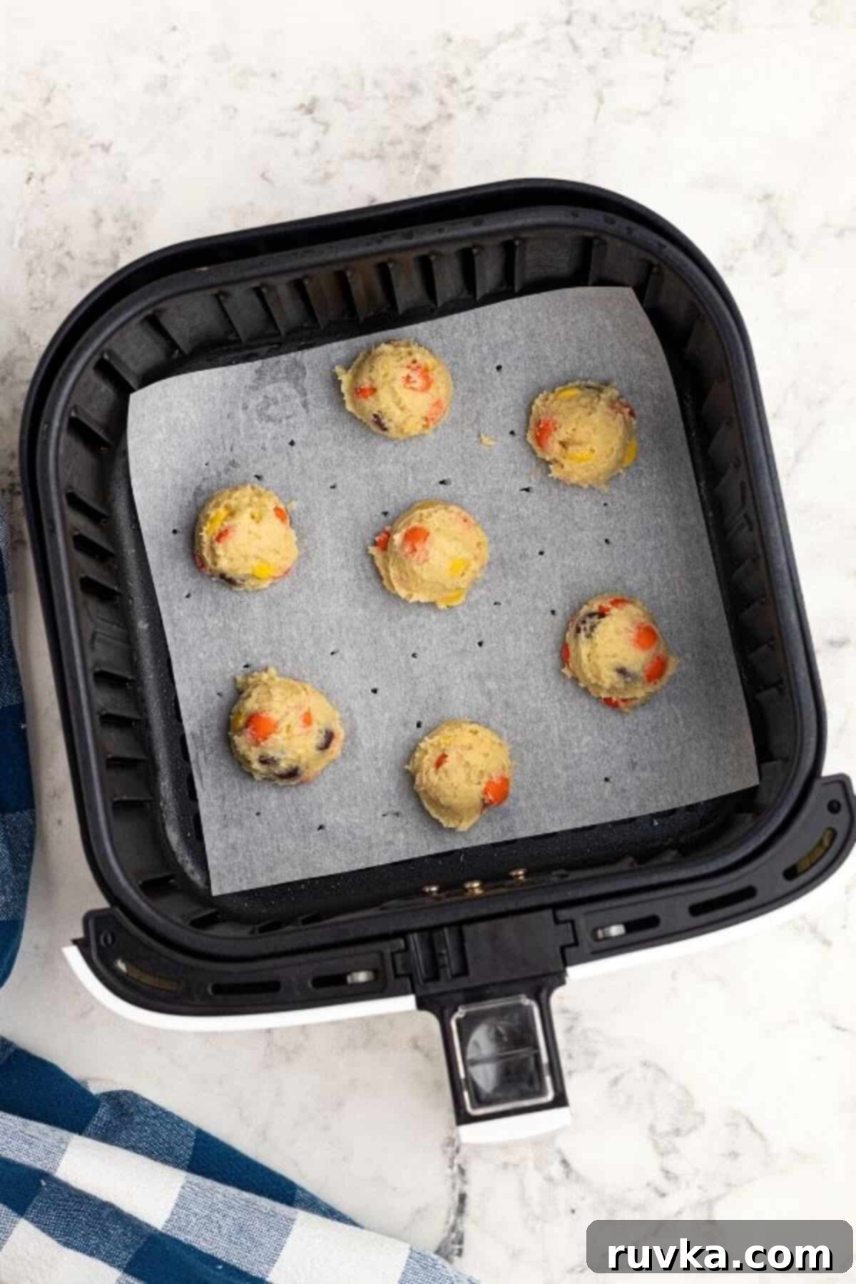 Easy Air Fryer Sugar Cookies 3 Cookie dough scooped into the air fryer basket onto parchment paper before cooking.