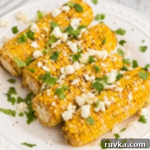 Crispy Air Fryer Elote 8 Close up of air fryer Mexican street corn on a white plate ready to serve.