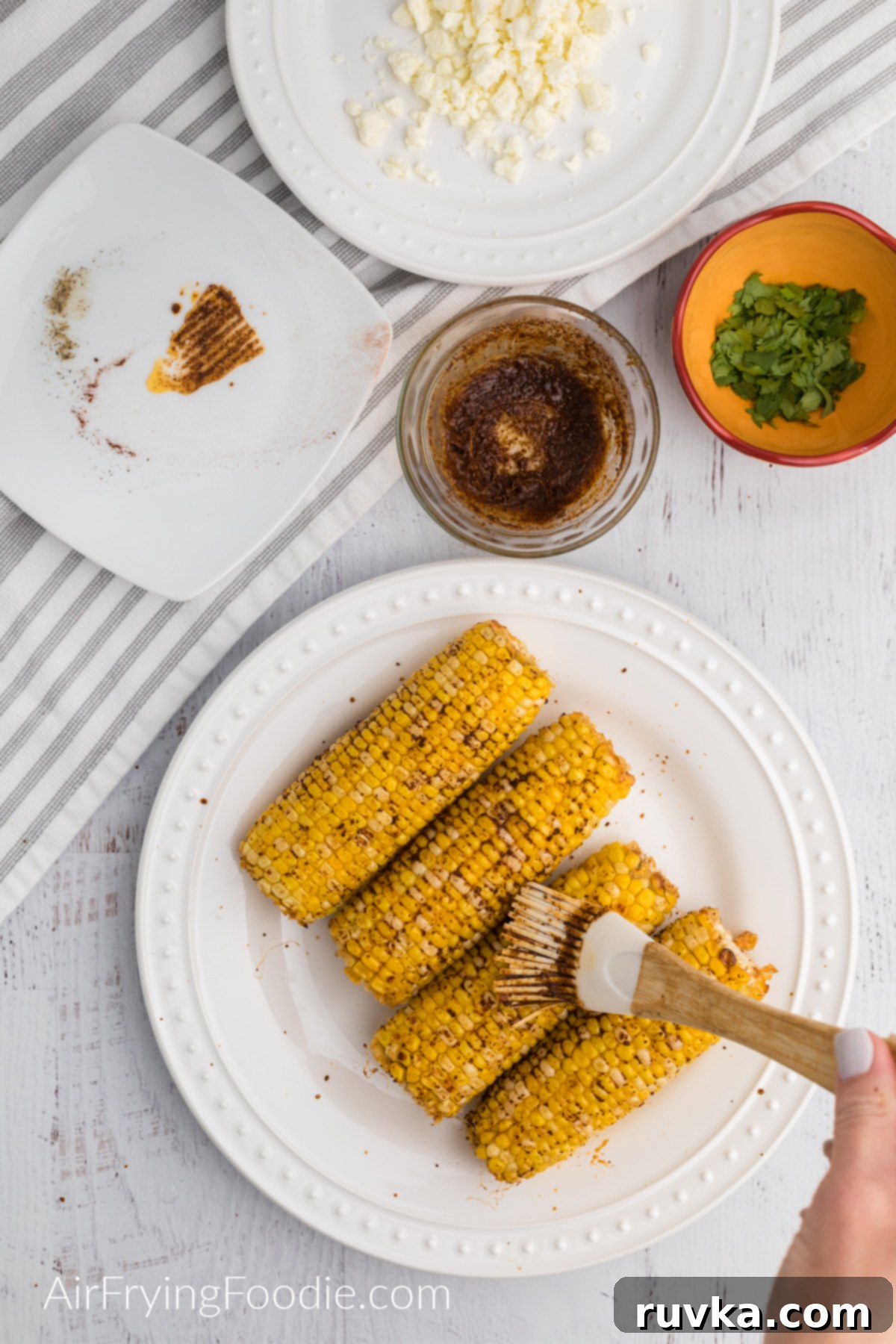 Crispy Air Fryer Elote 5 Brushing the cooked corn with the seasoned butter.