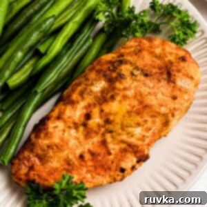 Perfect Air Fryer Chicken Breast 7 Golden, air fried chicken on a white plate with green beans.