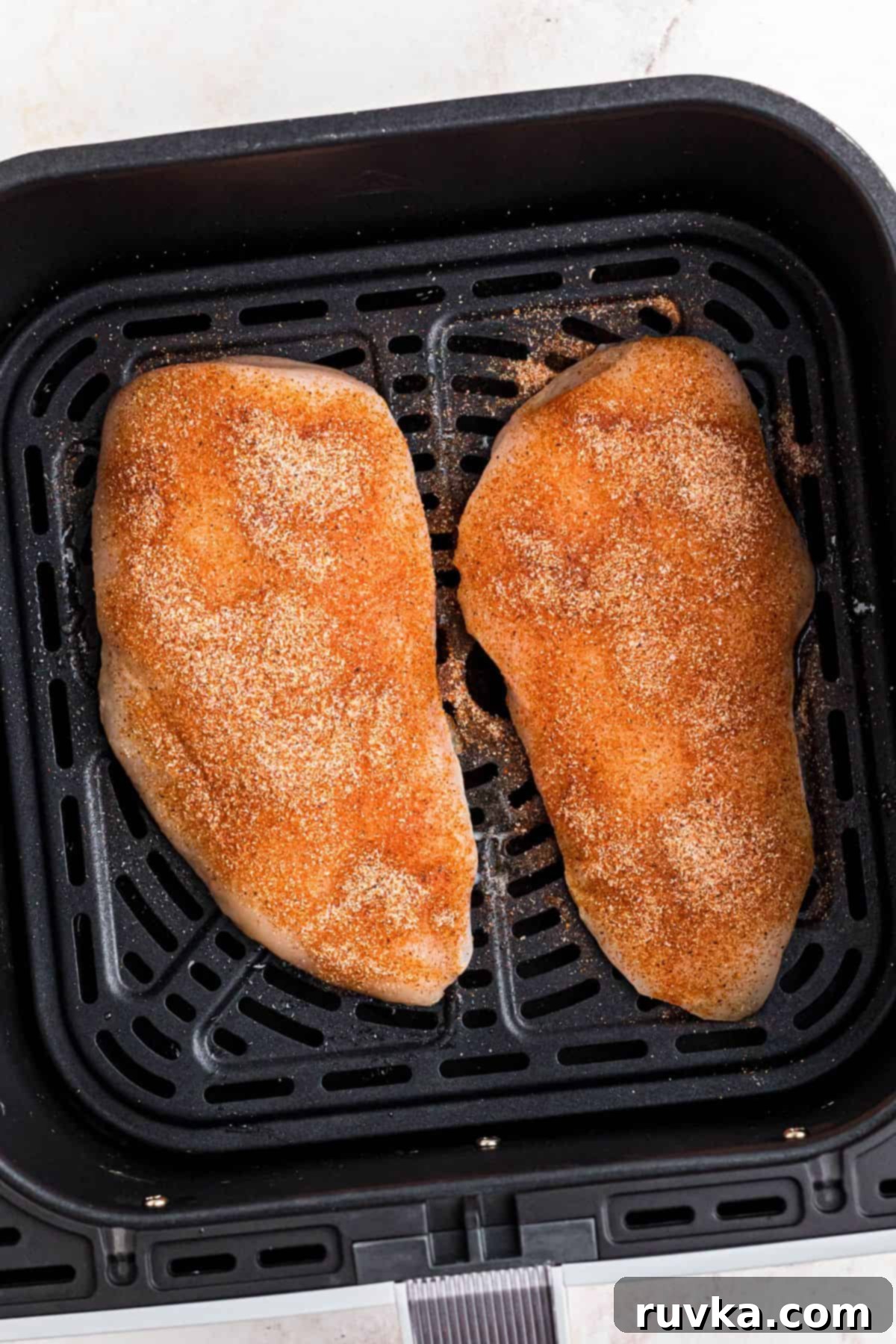 Perfect Air Fryer Chicken Breast 5 Uncooked chicken that has been seasoned, in the air fryer basket.