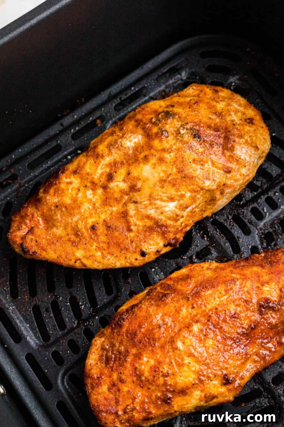 Perfect Air Fryer Chicken Breast 6 Golden, seasoned chicken breast in the air fryer basket after being cooked.