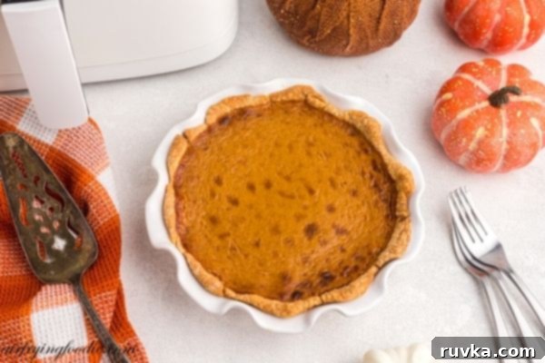 Air Fryer Pumpkin Pie 2 Golden pumpkin pie baked in a white pie plate with spatula and forks next to the pie.