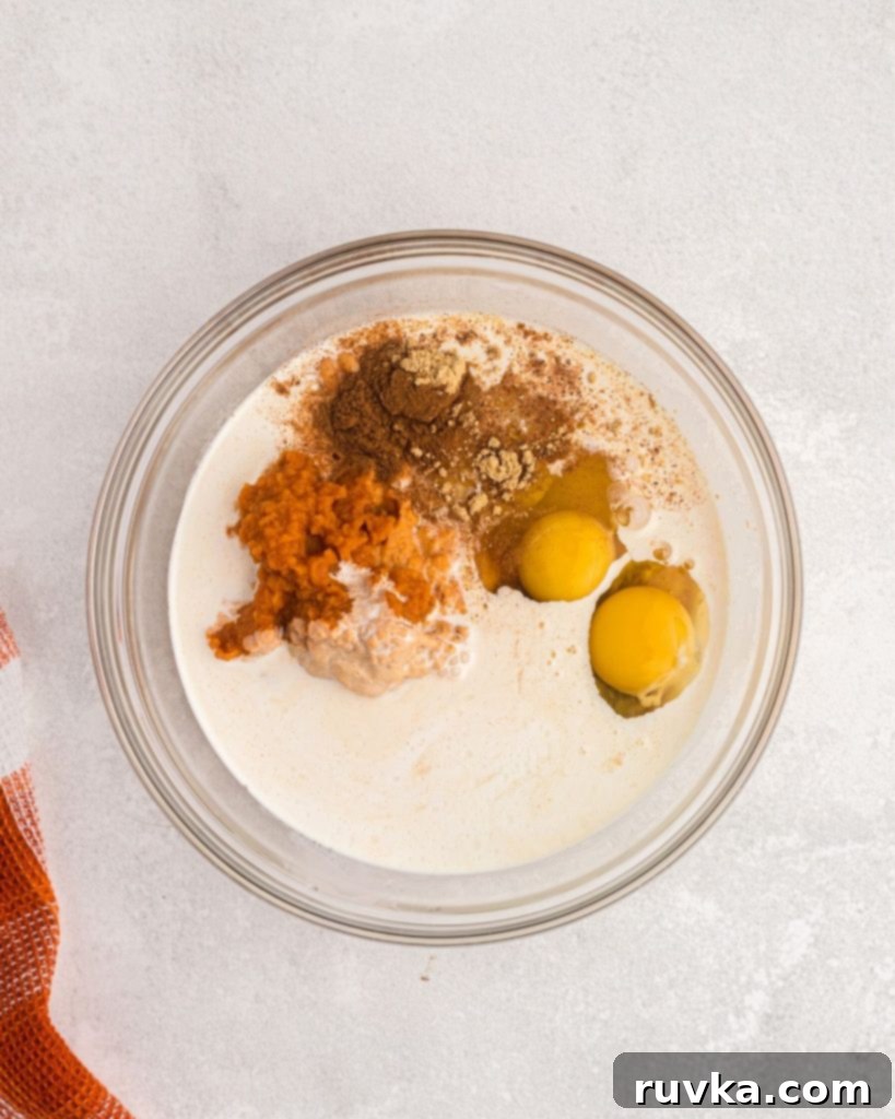 Air Fryer Pumpkin Pie 4 Clear glass bowl with pie filling ingredients before being mixed together.