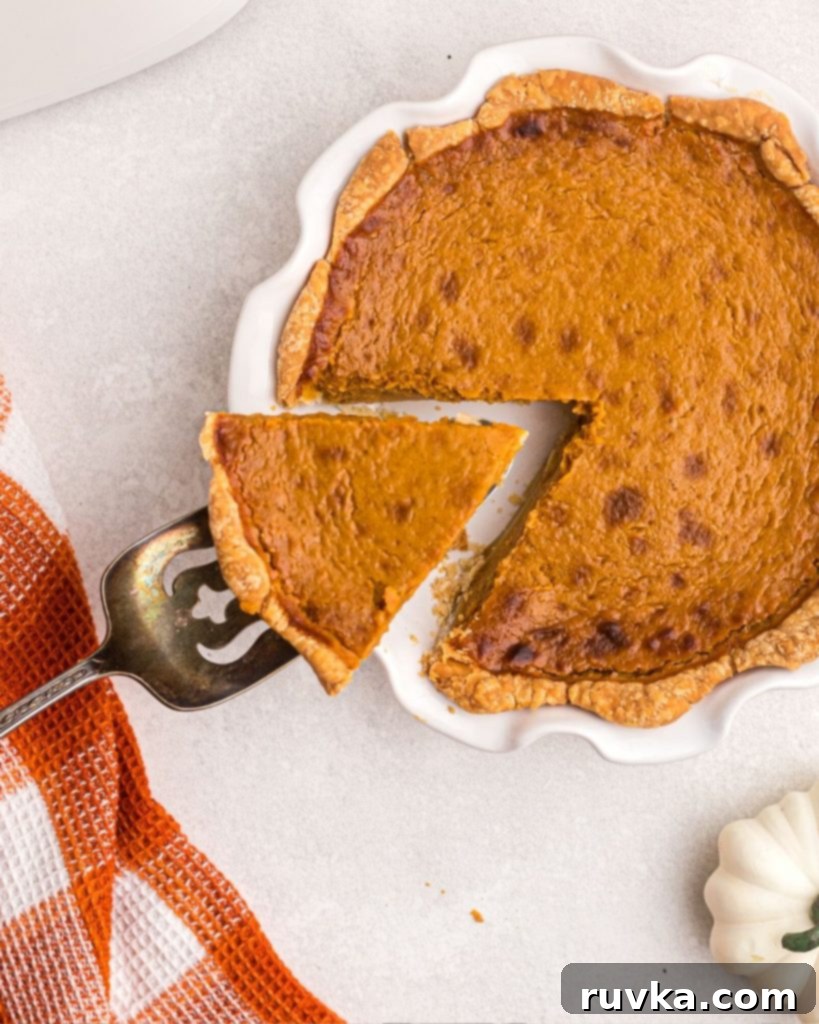Air Fryer Pumpkin Pie 8 Cooked pumpkin pie with a slice being lifted on an antique spatula.