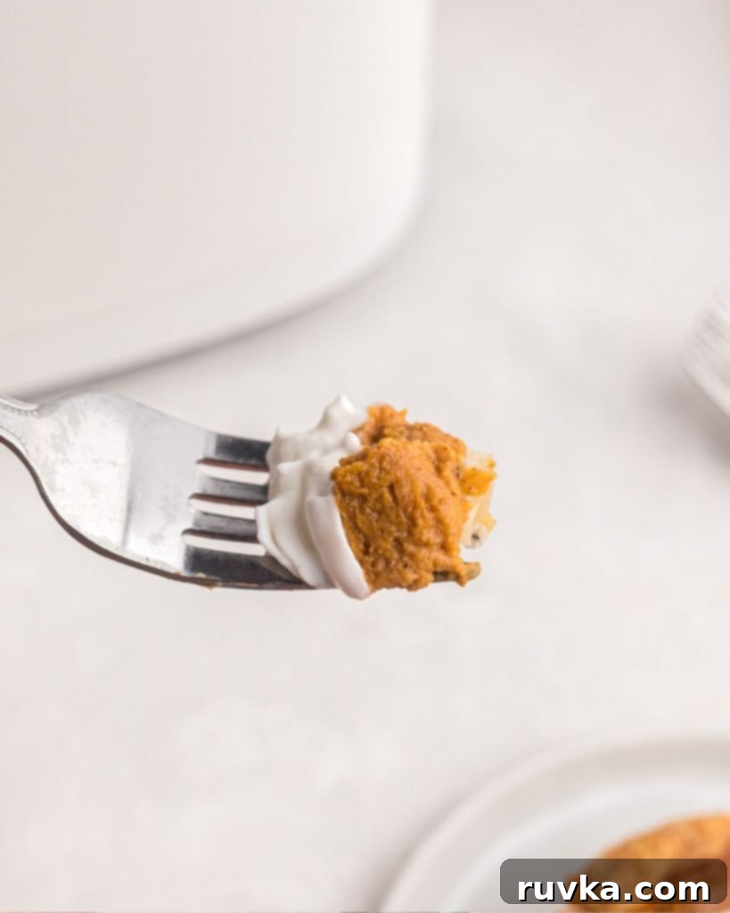 Air Fryer Pumpkin Pie 9 Bite size of pumpkin pie on a fork with whipped cream on top.