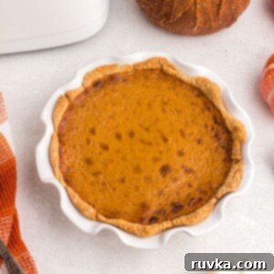 Air Fryer Pumpkin Pie 10 Golden orange pie in a white pie plate after being cooked in the air fryer.