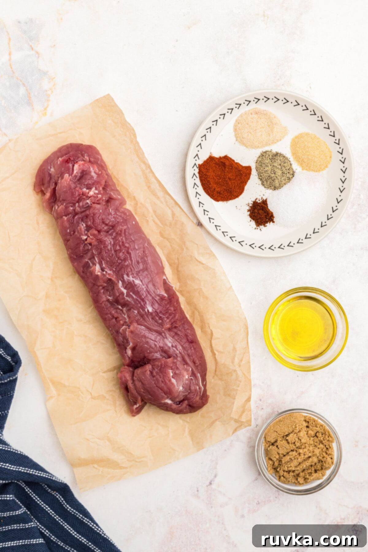 Tender Air Fryer Pork Tenderloin in a Flash 3 Uncooked pork tenderloin with olive oil, brown sugar, and other seasonings, measured out on a marble table.