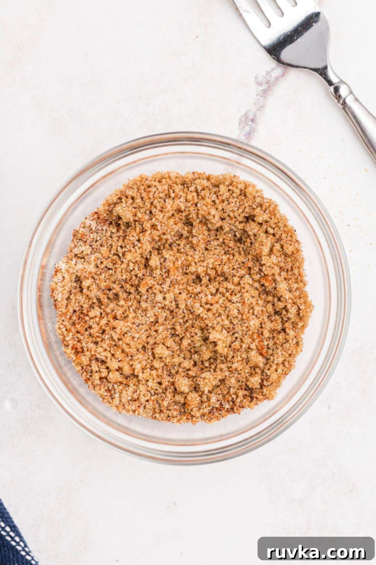 Tender Air Fryer Pork Tenderloin in a Flash 5 Seasonings mixed in a small glass bowl with a fork, on a marble table.