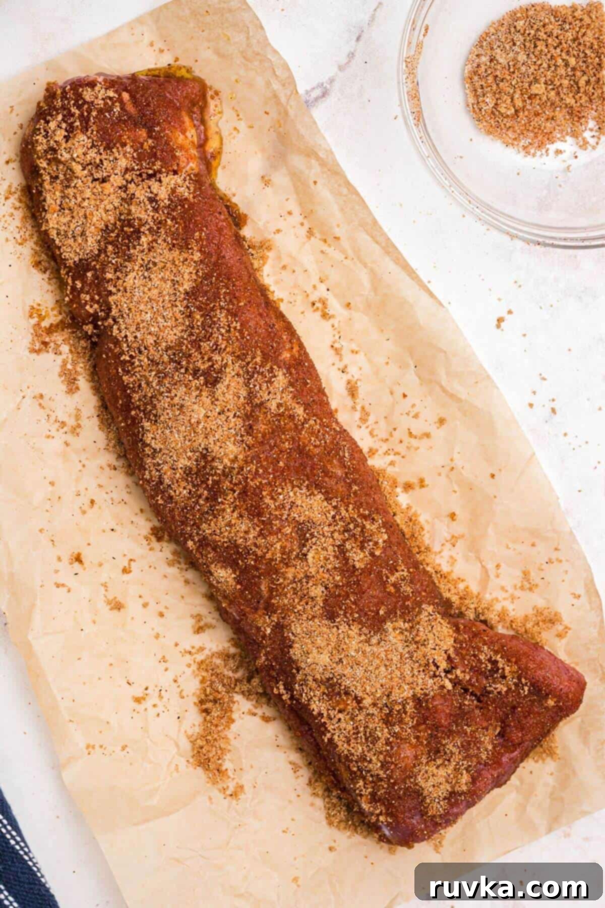 Tender Air Fryer Pork Tenderloin in a Flash 6 Uncooked pork tenderloin on light brown butcher paper, after being seasoned with brown sugar and spices.
