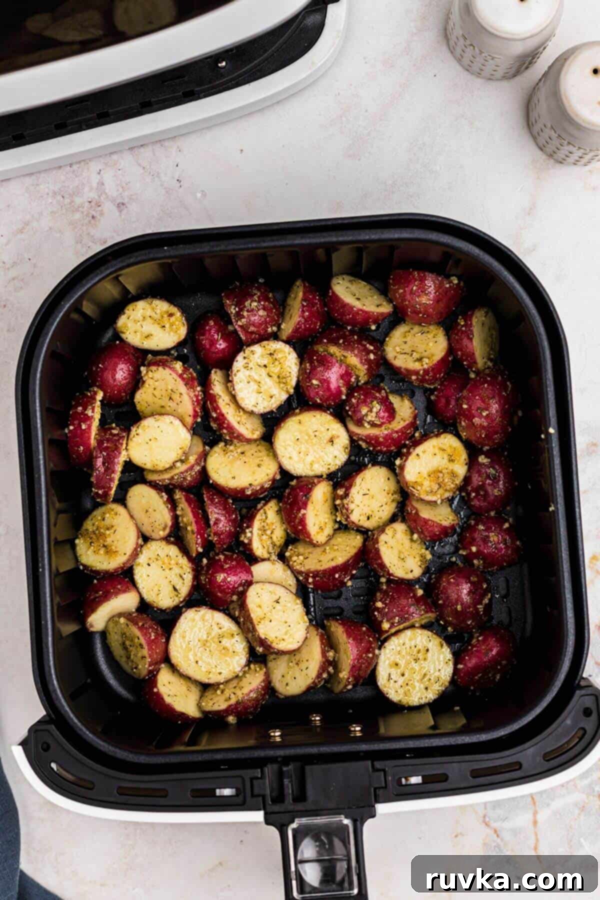 Crispy Air Fryer Potatoes 6 Seasoned uncooked baby red potatoes in the air fryer basket before being cooked.