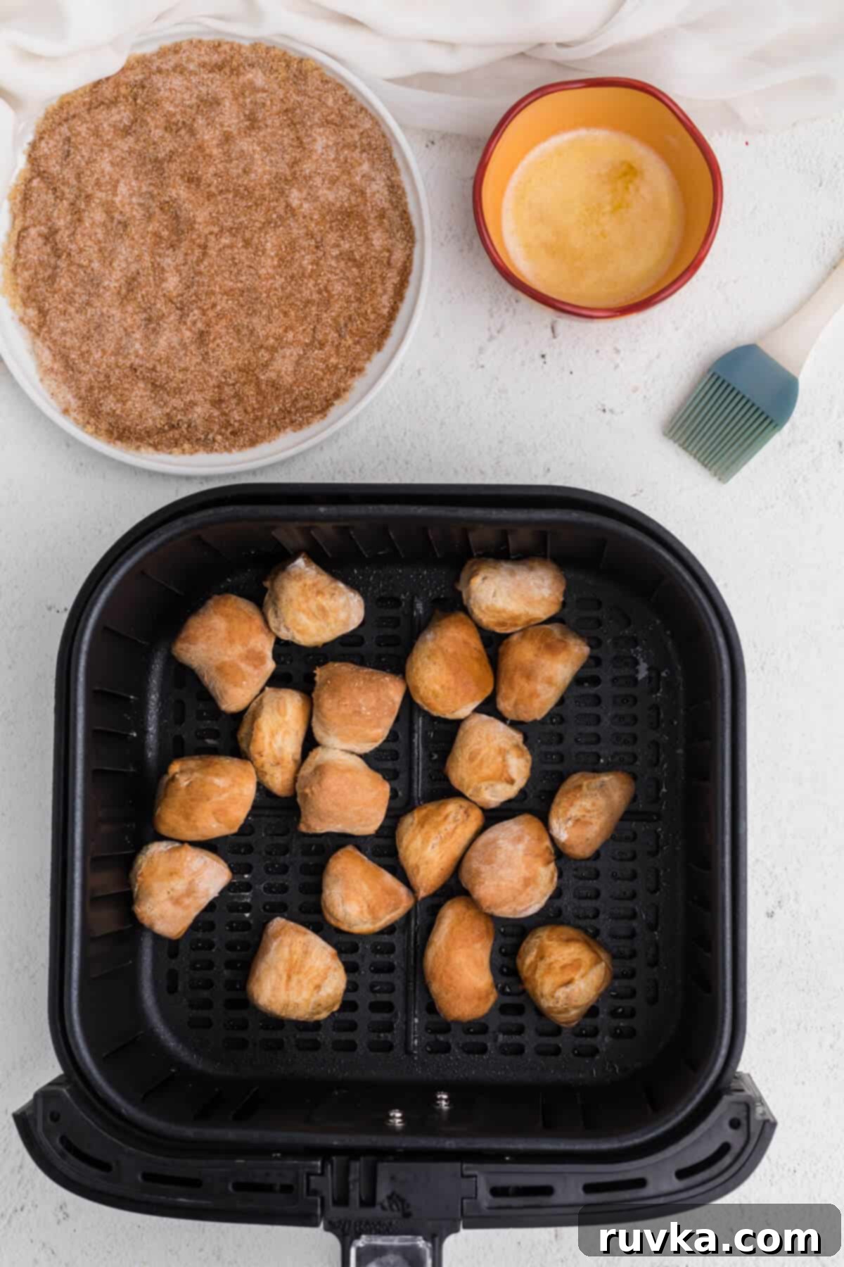 Air Fried Pretzel Perfection 9 Pretzel bites in air fryer basket ready to be brushed with butter and dipped into cinnamon and sugar mixture.