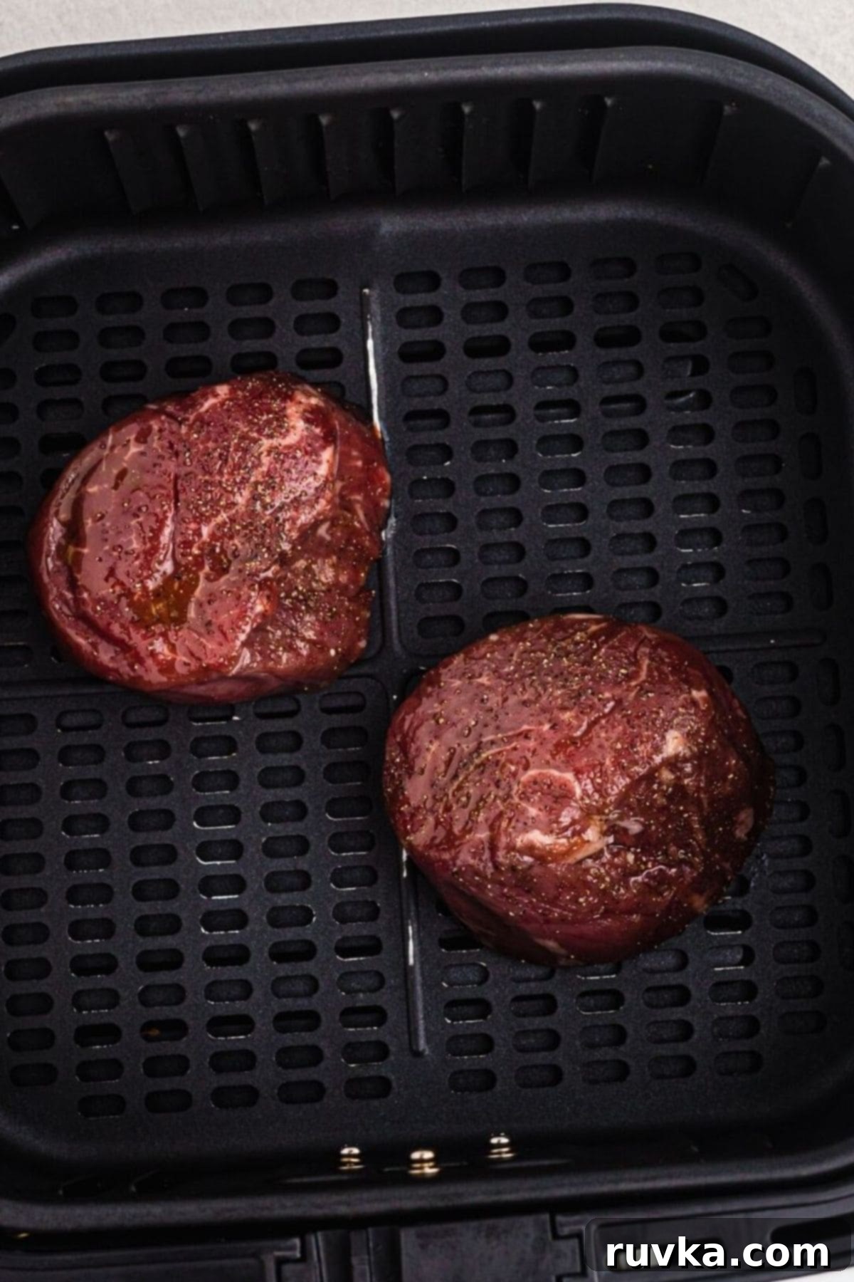 Perfect Air Fryer Filet Mignon 4 Uncooked filets in the air fryer basket after being seasoned.
