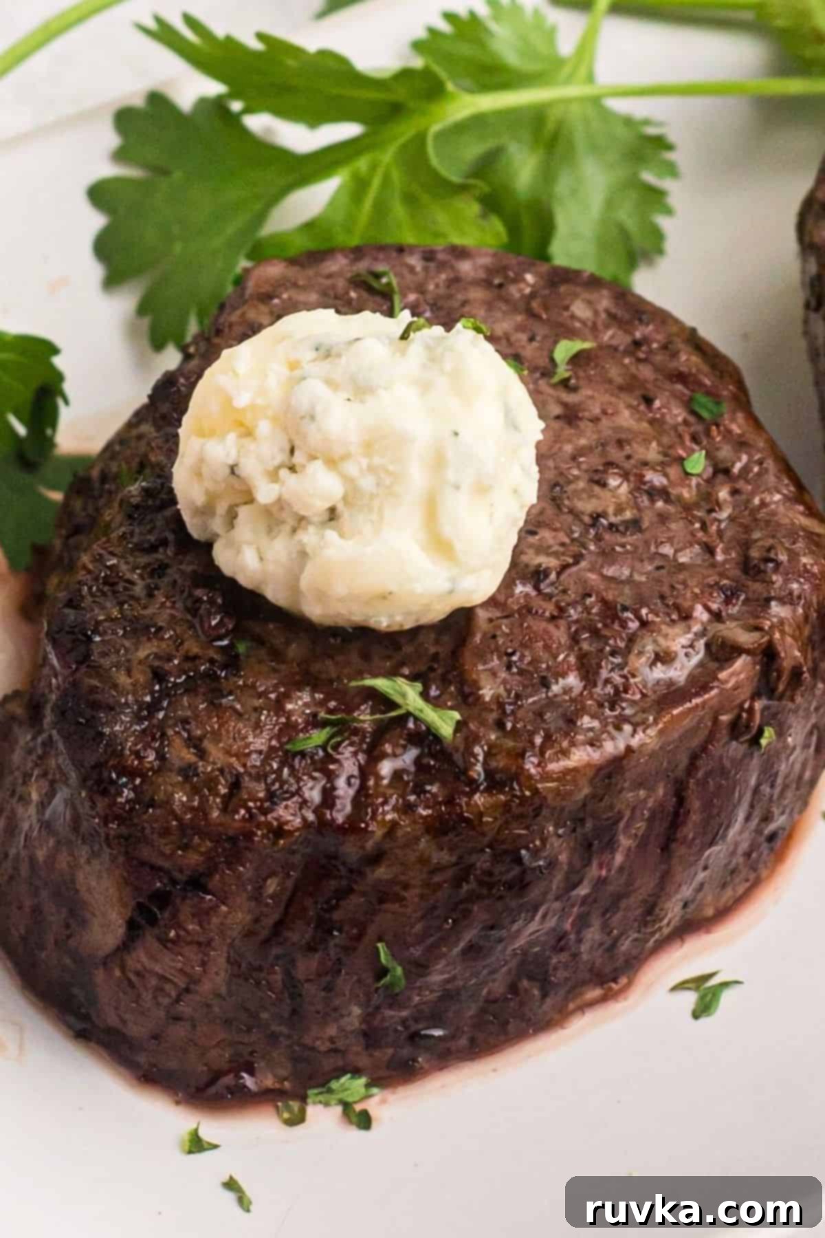 Perfect Air Fryer Filet Mignon 5 Filet topped with compound butter on a white plate.