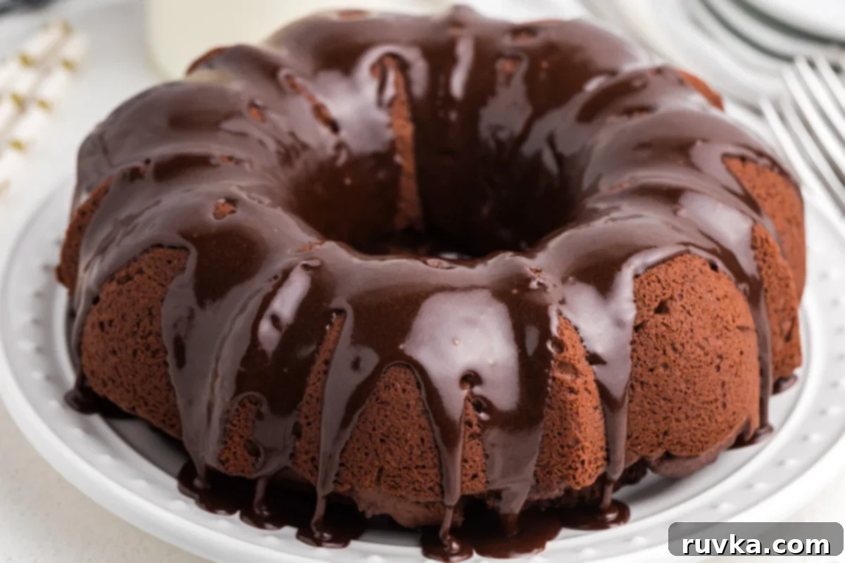 Irresistible Air Fryer Chocolate Bundt 9 A beautiful slice of Air Fryer Chocolate Bundt Cake, generously topped with chocolate frosting and presented on a white plate, ready to be eaten.