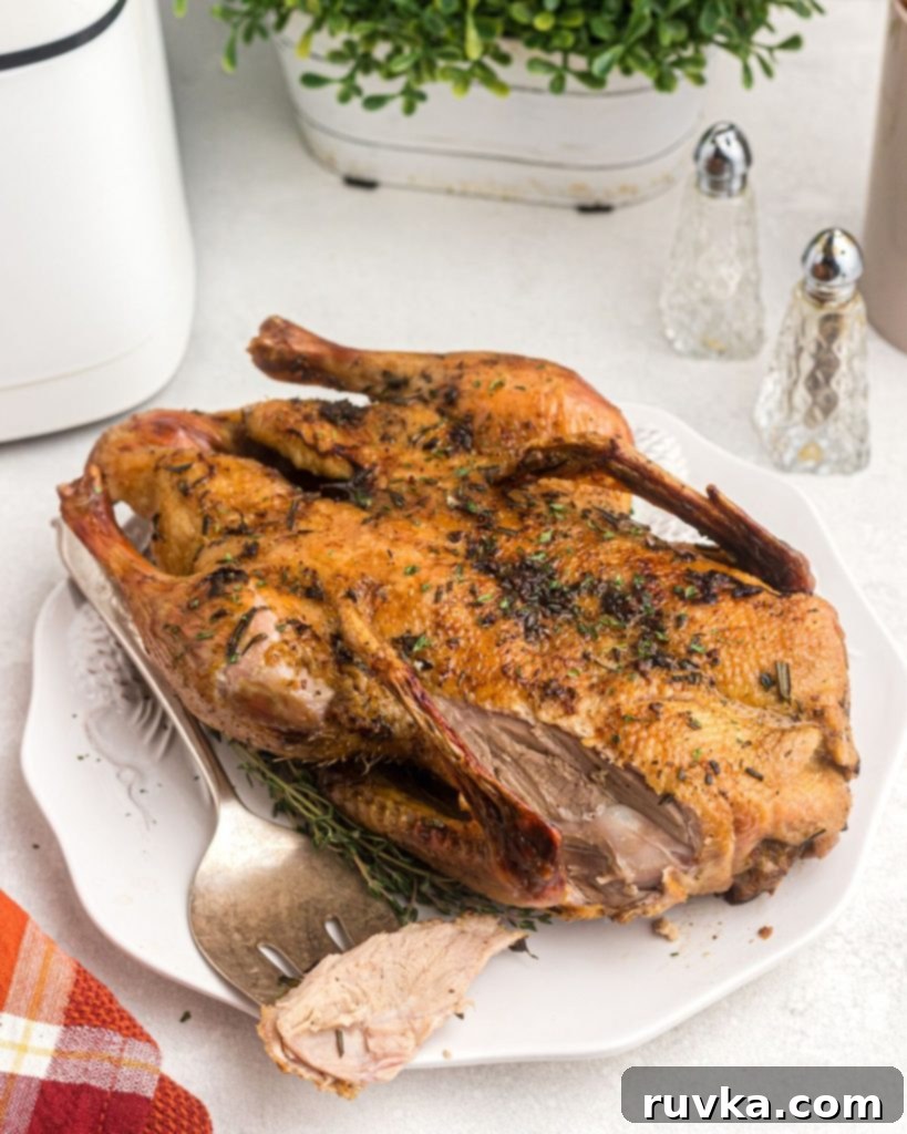 Crispy Air Fryer Duck 3 Golden duck on a white platter with a slice cut and on a fork.