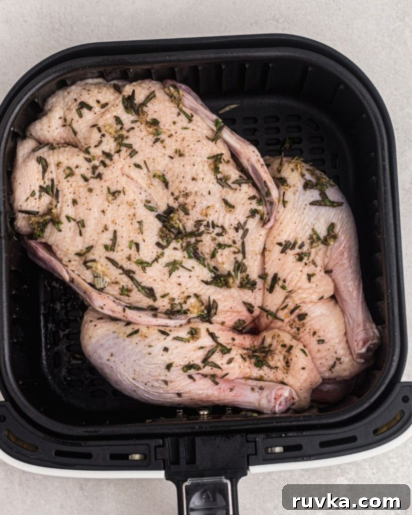 Crispy Air Fryer Duck 7 Uncooked duck in an air fryer basket, seasoned before being cooked.
