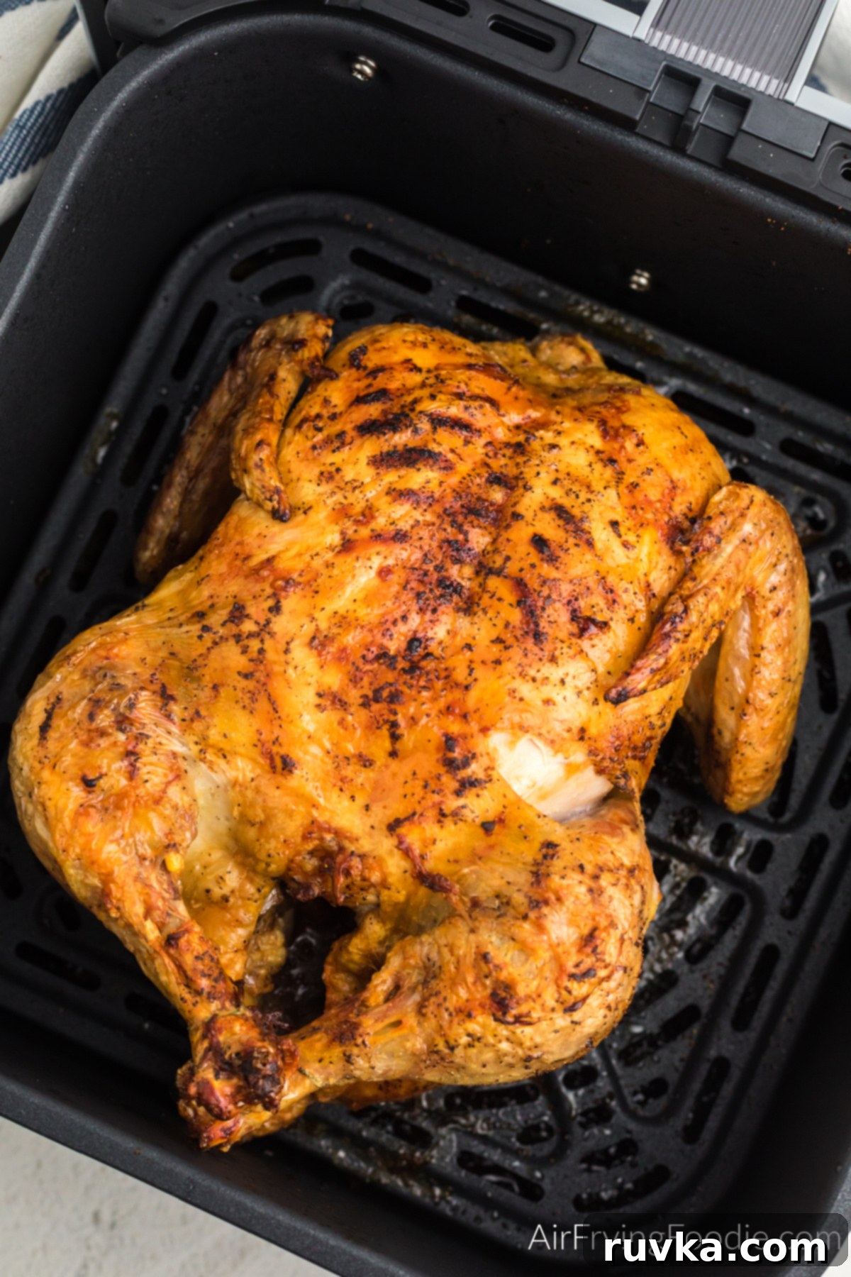 Crispy Air Fryer Whole Chicken 3 Close up photo of air fried whole chicken in air fryer basket.