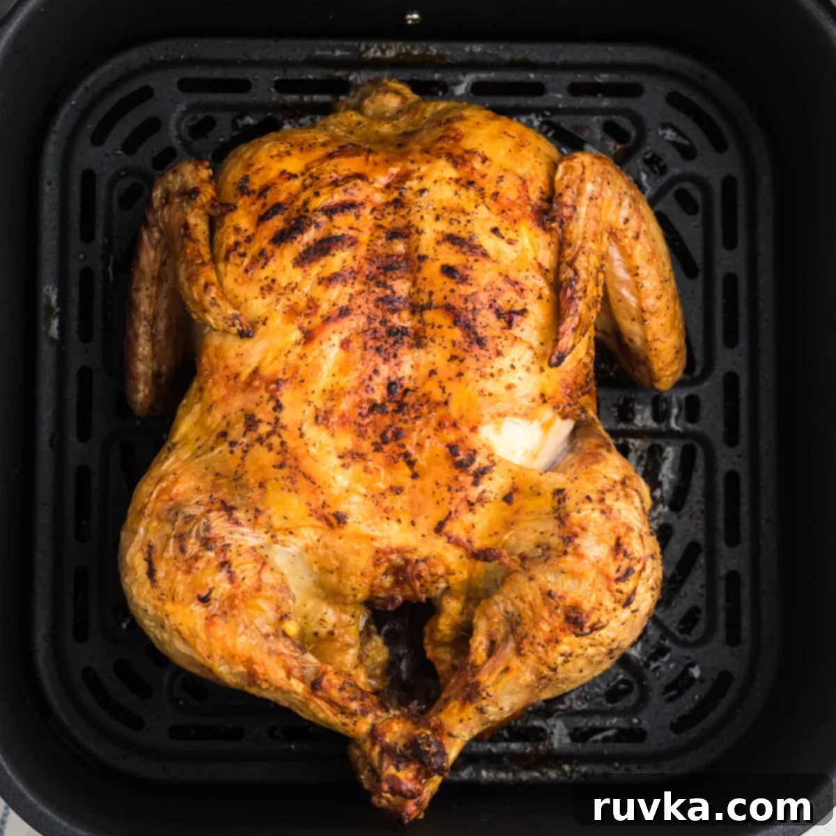 Crispy Air Fryer Whole Chicken 5 Air fryer whole chicken fully cooked and in the basket of the air fryer.