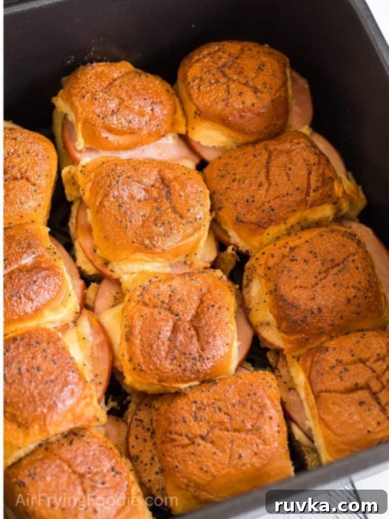 Irresistible Air Fryer Ham and Cheese Sliders 2 Golden brown ham and cheese sliders perfectly cooked in an air fryer basket, ready to be served.