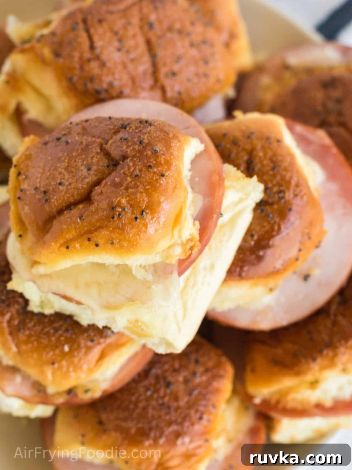 Irresistible Air Fryer Ham and Cheese Sliders 9 Close-up of perfectly stacked, golden-brown ham and cheese sliders on a plate, showcasing their melted cheese and inviting glaze, ready to be enjoyed.
