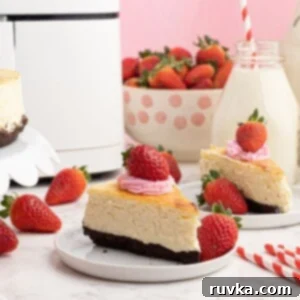 Effortless Air Fryer Cheesecake 6 Creamy sliced piece of cheesecake, with a chocolate crust, served with strawberries on a white plate in front of an air fryer.