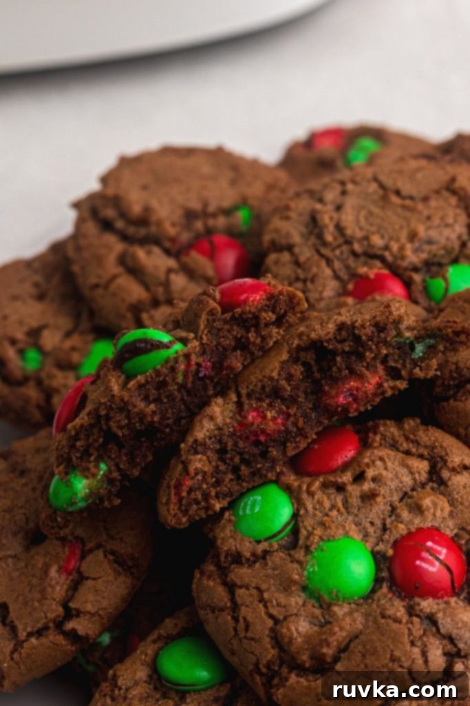 Quick Christmas Air Fryer Brownie Bites 3 Close-up of freshly baked brownie cookies adorned with festive Christmas candies, with one cookie gently broken in half to reveal its soft, fudgy interior.