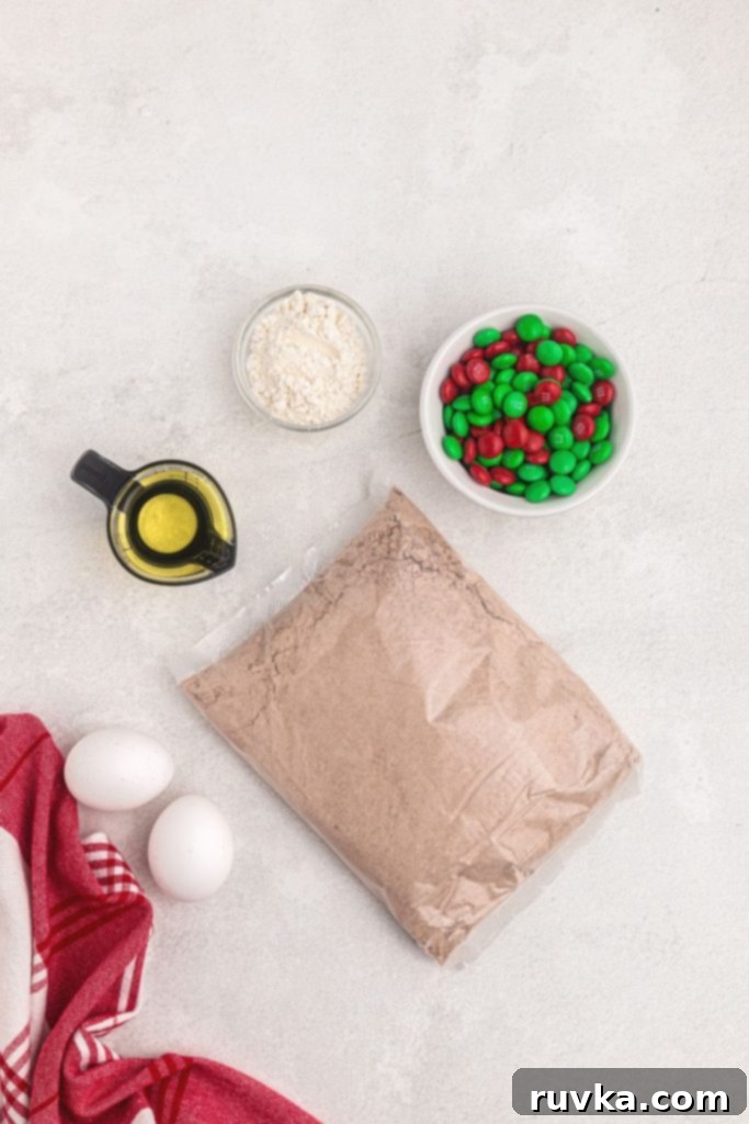 Quick Christmas Air Fryer Brownie Bites 4 A flat lay photograph showcasing the simple yet essential ingredients needed to create festive brownie mix cookies: a box of brownie mix, vegetable oil, all-purpose flour, eggs, and a colorful assortment of holiday candies.