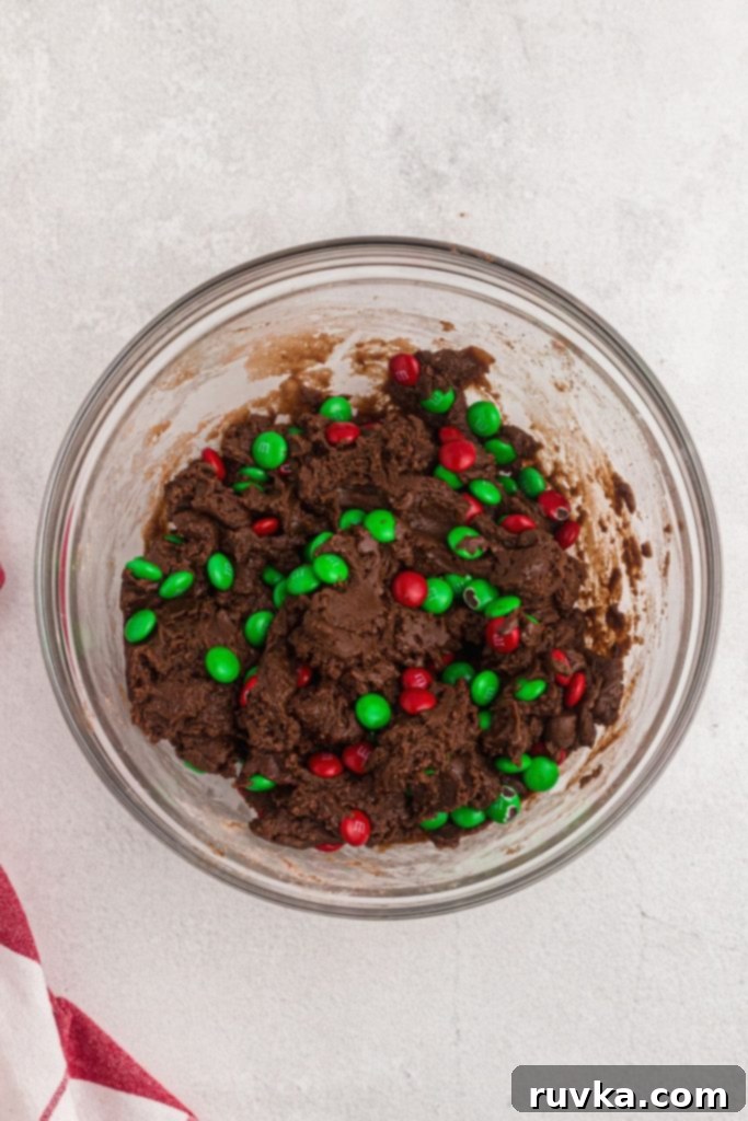 Quick Christmas Air Fryer Brownie Bites 5 Rich, fudgy brownie batter expertly mixed with vibrant holiday candies, ready to be scooped and baked into delicious cookies.