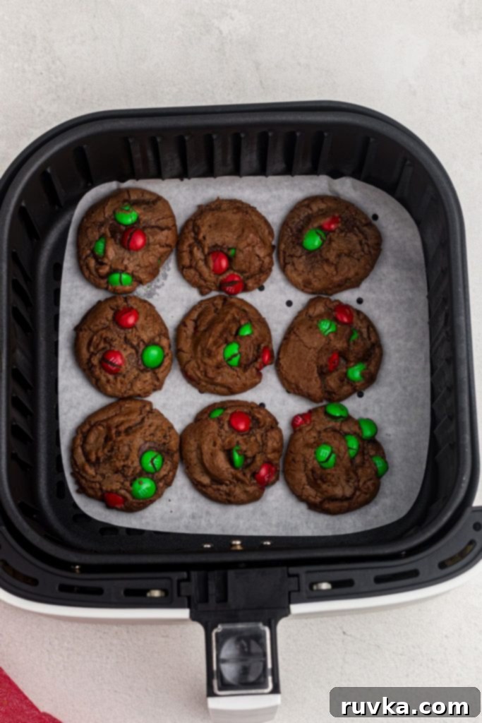 Quick Christmas Air Fryer Brownie Bites 7 Perfectly baked brownie cookies, still warm and featuring melted Christmas candies, resting in the air fryer basket after being cooked, showcasing their soft and chewy texture.