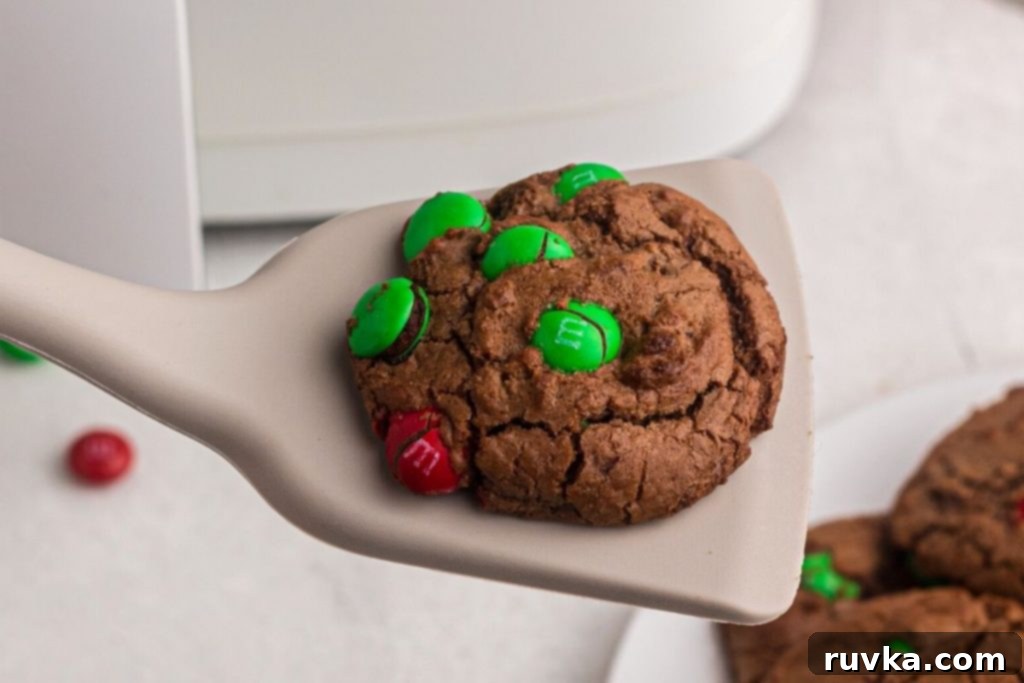 Quick Christmas Air Fryer Brownie Bites 8 A perfectly baked, warm brownie cookie, delicately held on a spatula, with a blurred air fryer in the background, ready for serving.