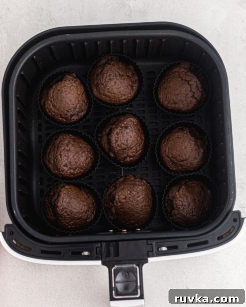 Spooktacular Air Fryer Ghost Cupcakes 5 Cooked chocolate cupcakes in an air fryer basket.