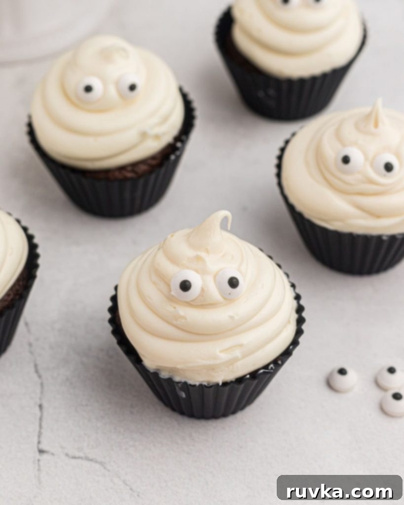 Spooktacular Air Fryer Ghost Cupcakes 7 Ghost cupcakes as they are being made with candy eyes on the table.