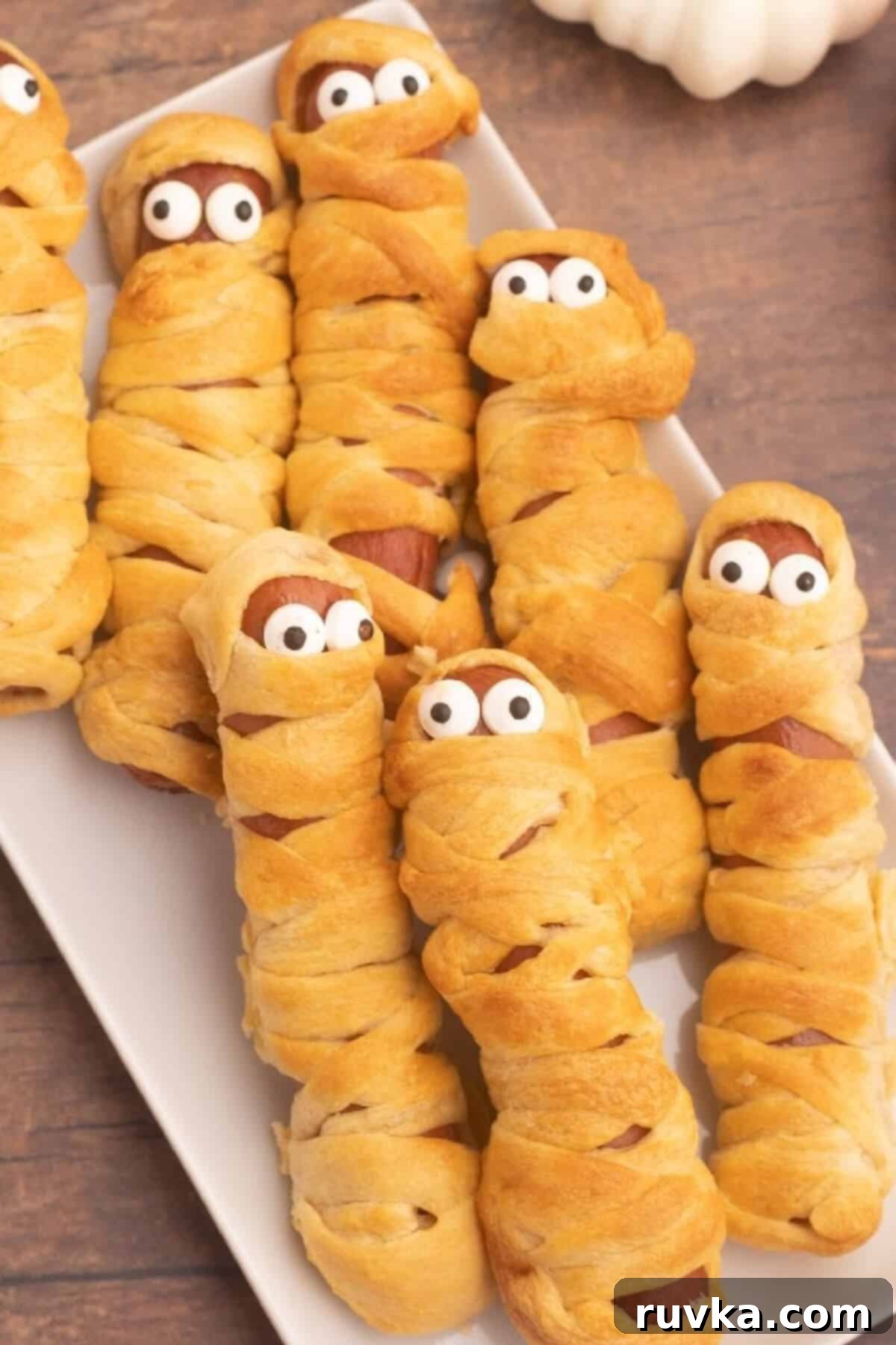 Spooky Air Fryer Hot Dog Mummies 2 Golden brown Air Fryer Mummy Dogs, perfectly wrapped in crescent dough, with candy eyes peering out, ready for a Halloween party.