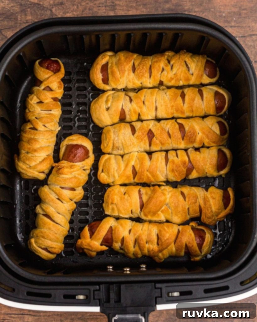 Spooky Air Fryer Hot Dog Mummies 7 A full air fryer basket showcasing freshly cooked Air Fryer Mummy Dogs, golden and slightly puffed, indicating they are perfectly done and ready to be served.