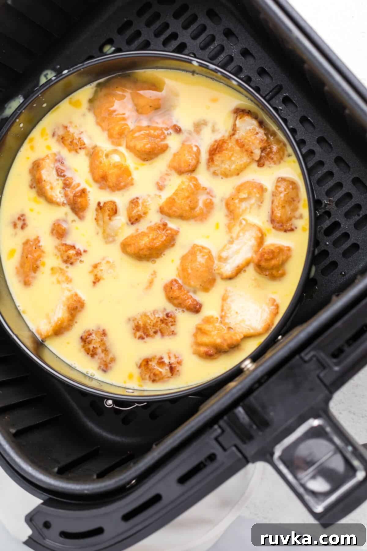 Crispy Air Fryer Breakfast Bowl 5 egg mixture with chicken nuggets and tater tots in the air fryer, ready to cook.