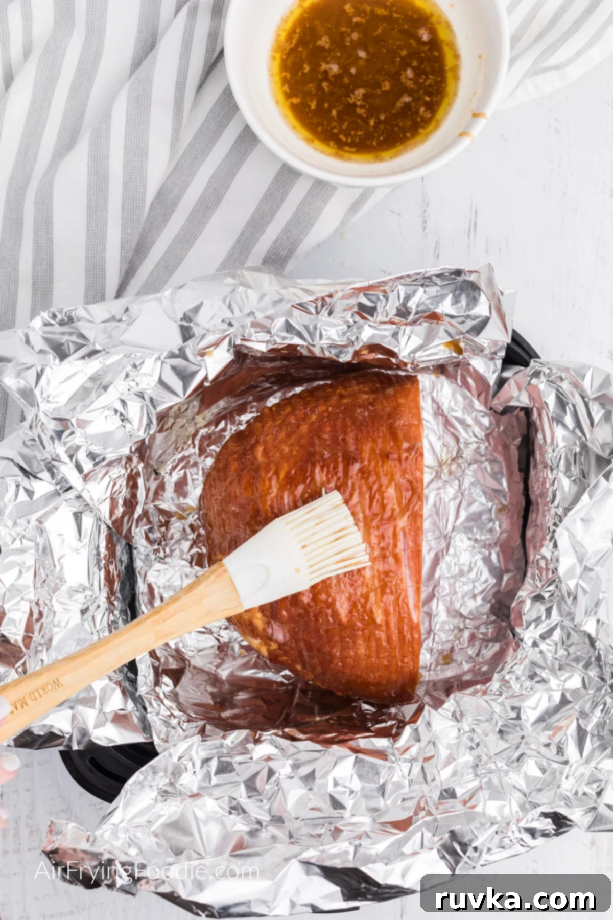 Crispy Air Fryer Ham 5 Ham being brushed with butter and brown sugar glaze, ready for the air fryer.