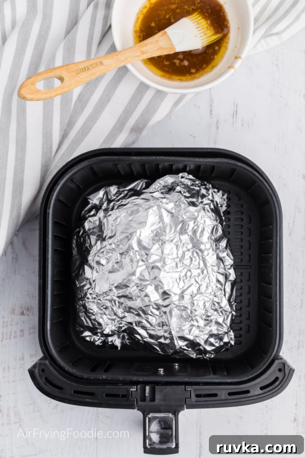 Crispy Air Fryer Ham 6 Ham wrapped in foil in the air fryer basket, cooking gently.