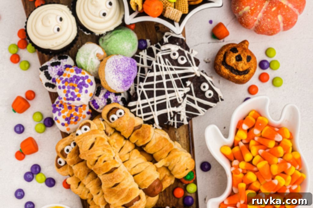 Spooktacular Air Fryer Charcuterie Board 3 Close-up of a festive Air Fryer Halloween Charcuterie Board featuring mummy dogs, ghost cupcakes, and various Halloween candies.