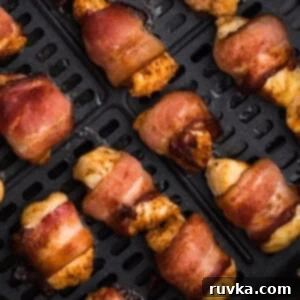 Perfectly Crispy Air Fryer Bacon Wrapped Chicken Bites 7 air fried bacon wrapped chicken bites in the basket of the air fryer.