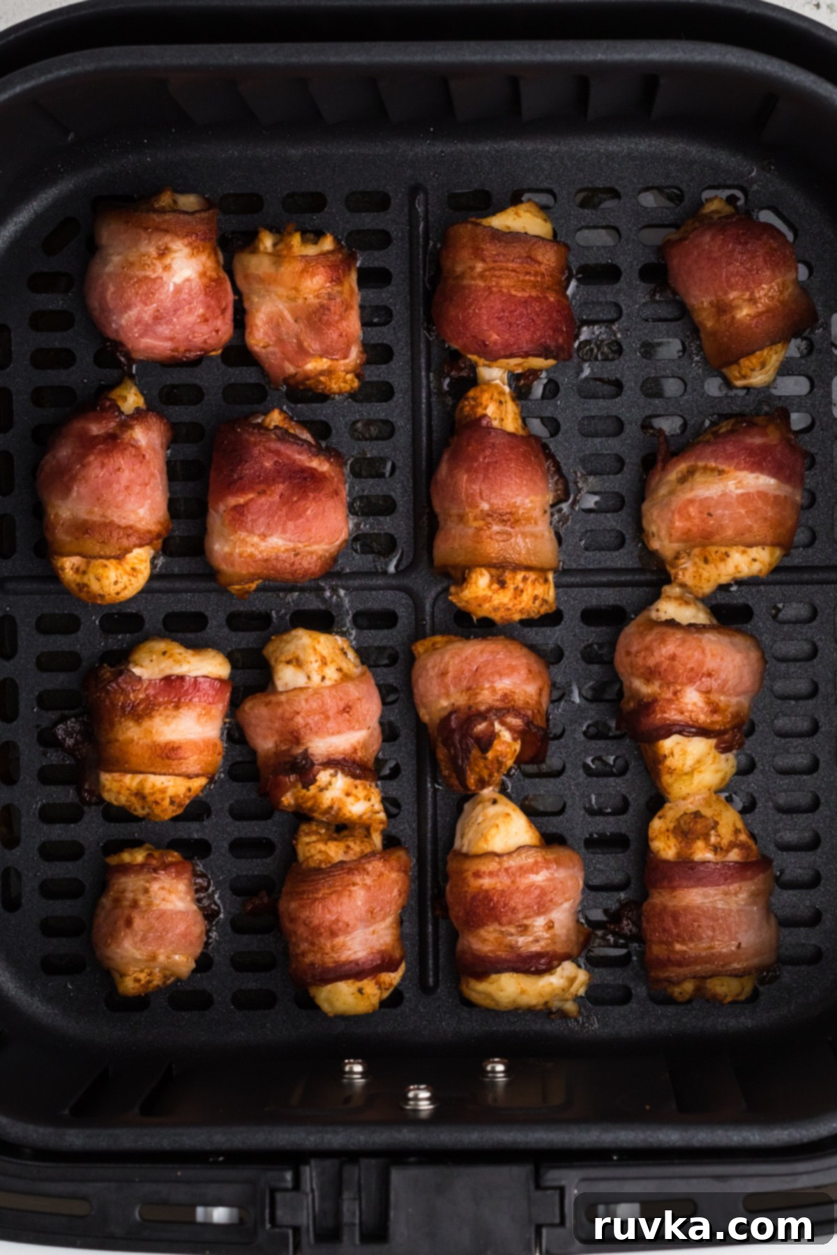 Perfectly Crispy Air Fryer Bacon Wrapped Chicken Bites 5 Fully cooked bacon wrapped chicken bites in the basket of the air fryer.
