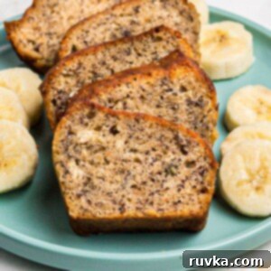 Golden moist bread sliced on a light green plate with slices of bananas.