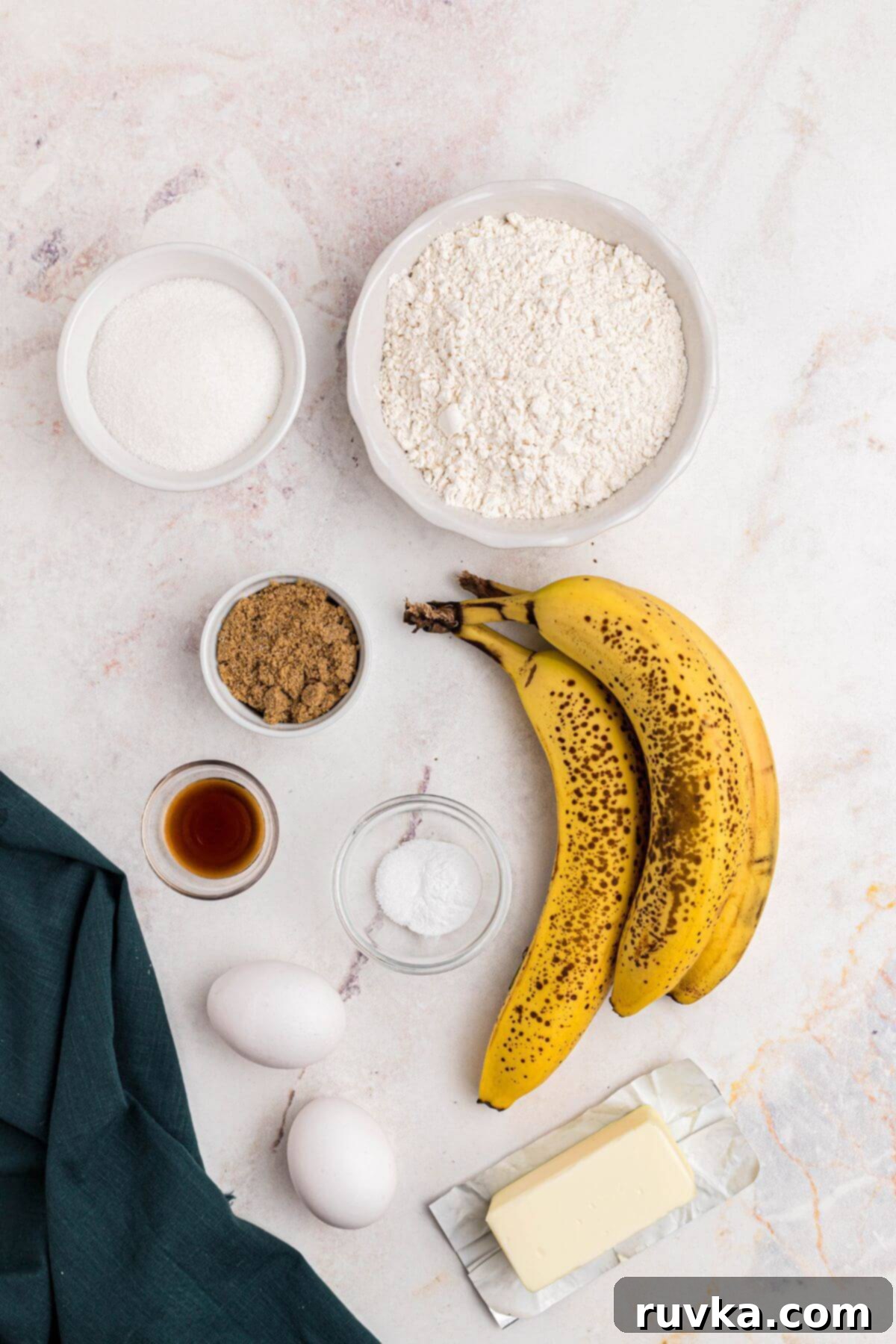 Ingredients for banana bread measured out on a marble table. 