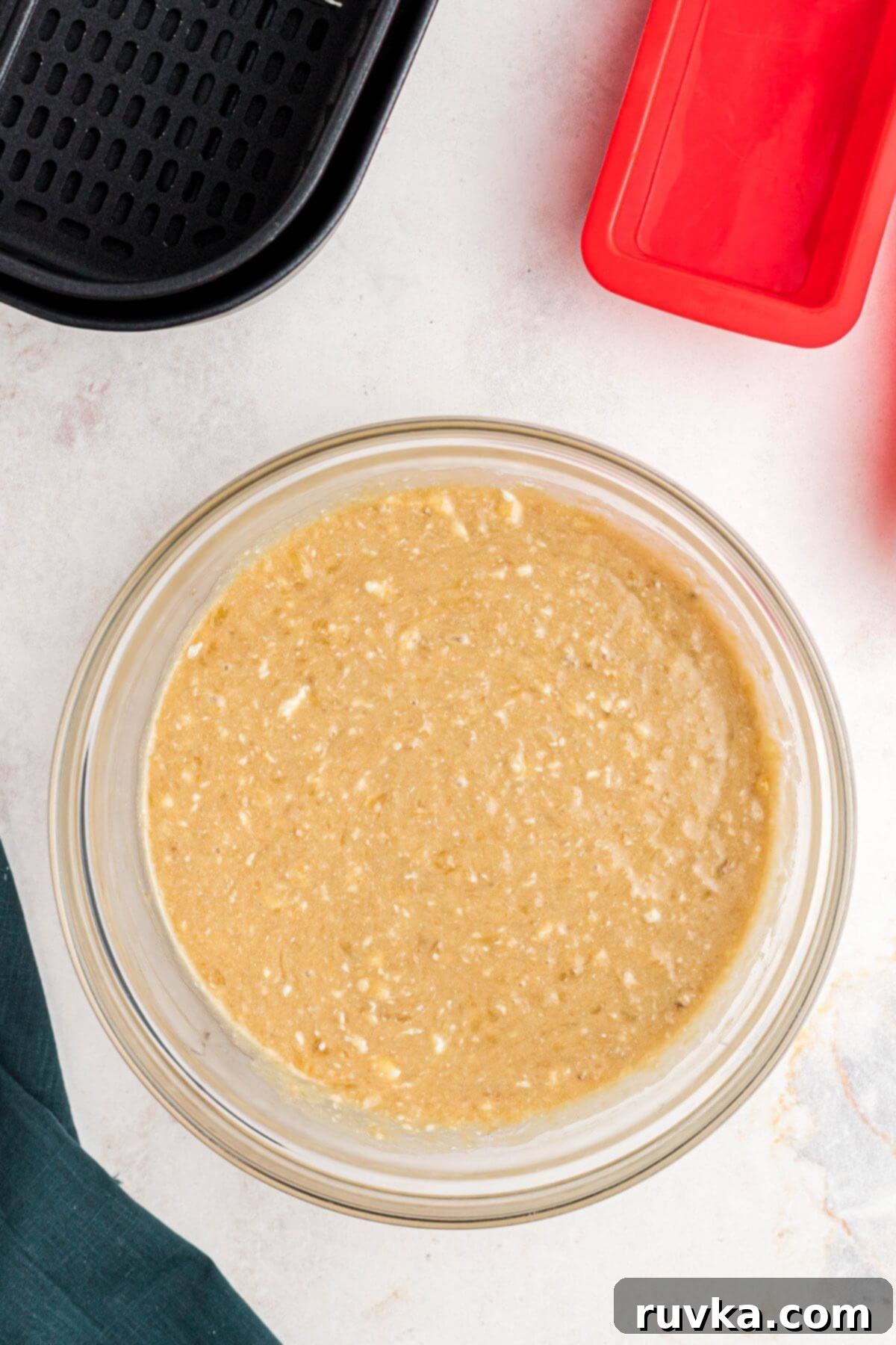Banana bread batter in a clear glass bowl after being well mixed. 