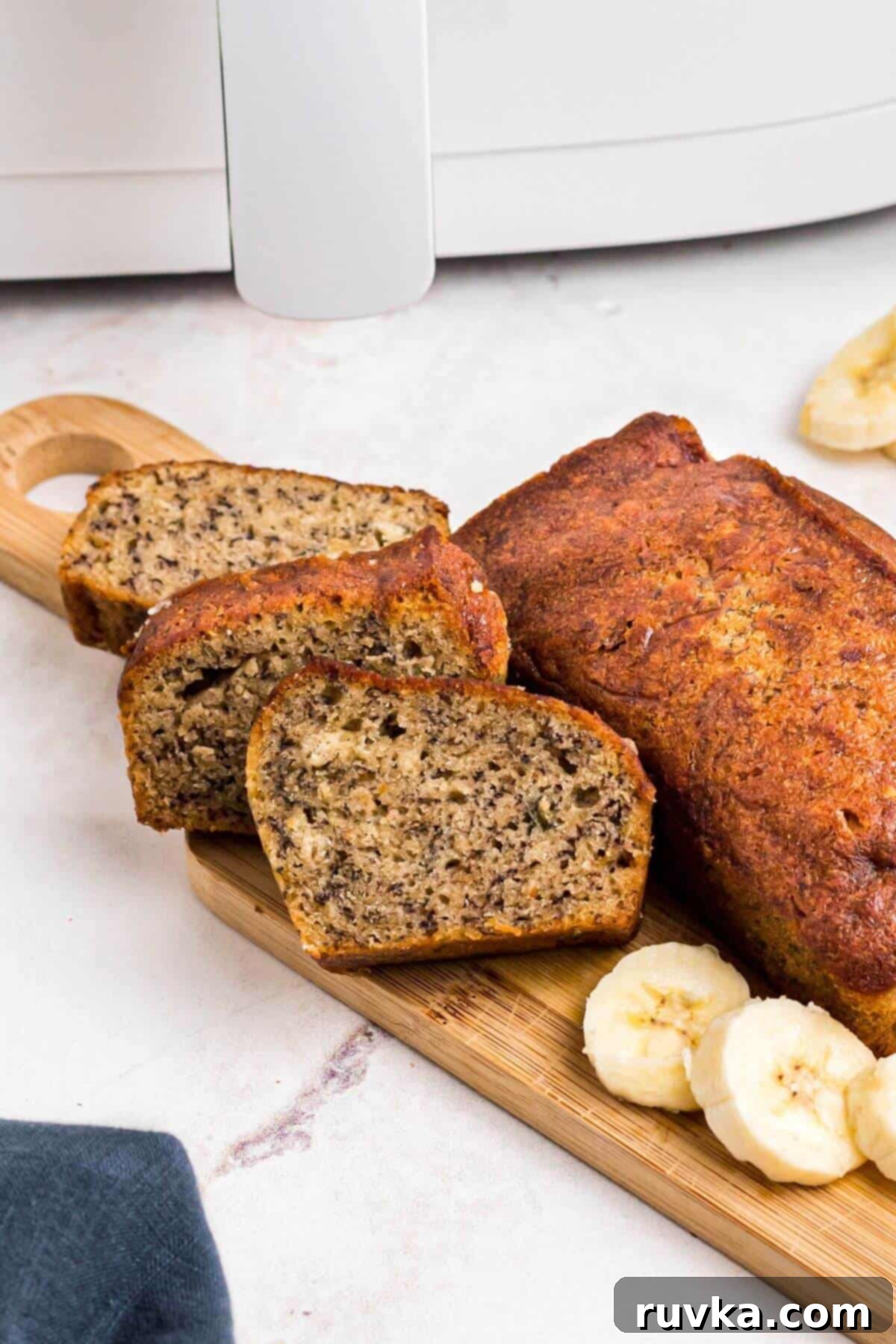 Golden baked banana bread on a wooden cutting board with banana slices. 