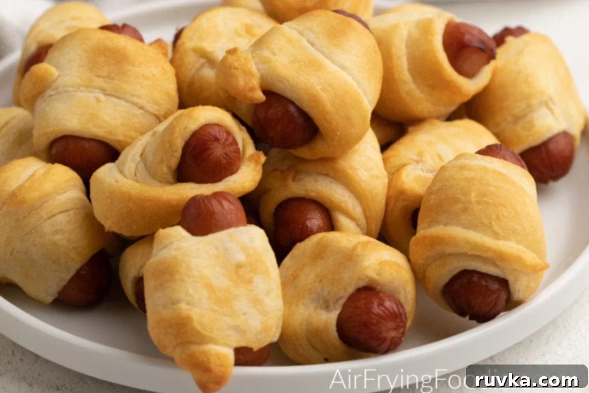 Golden Air-Fried Sausage Bites 6 Close up photo of air fryer pigs in a blanket on a white plate, highlighting their perfect golden brown crust.