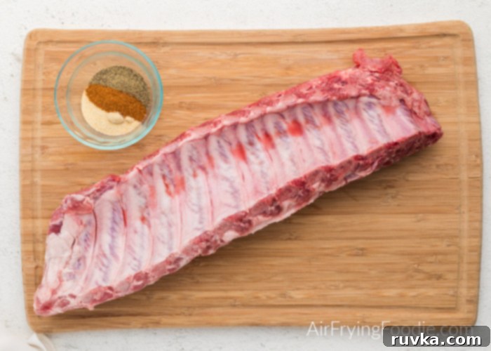 Ultimate Air Fryer BBQ Ribs 4 Slab of baby back ribs next to a bowl of spices and seasonings, ready for preparation.